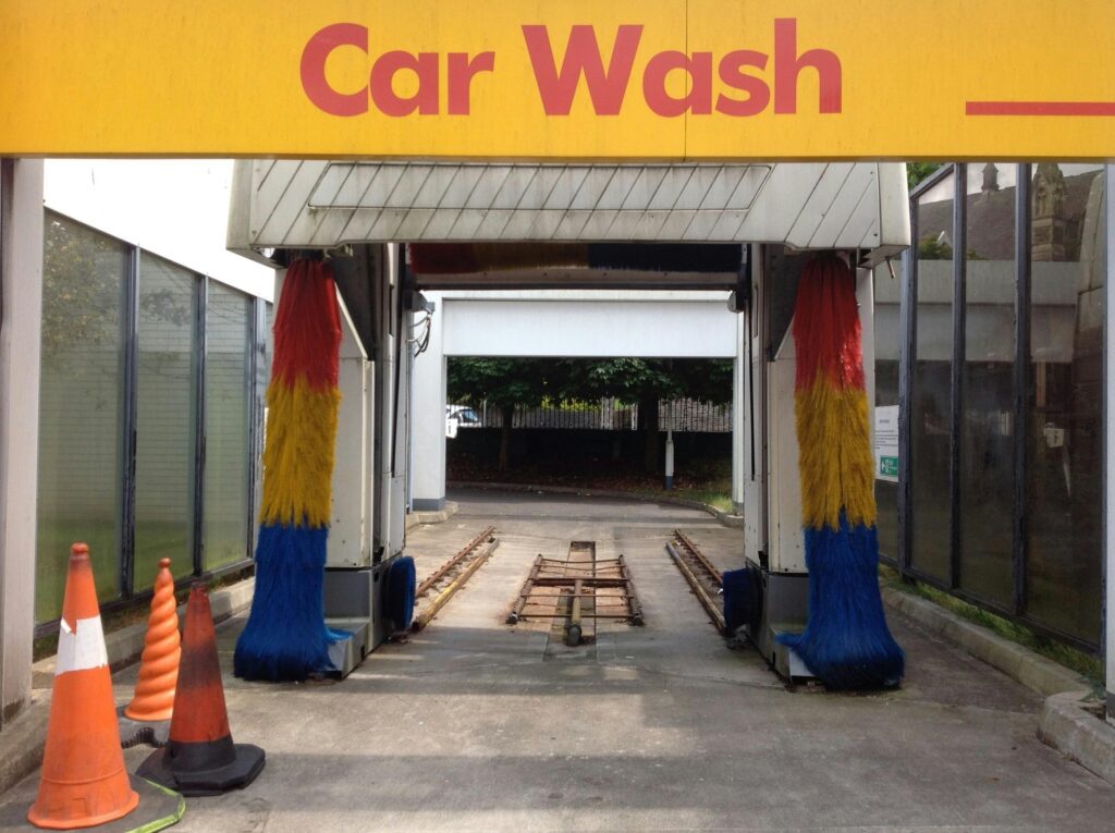 Image of an automatic car wash entrance featuring colorful brushes and traffic cones.